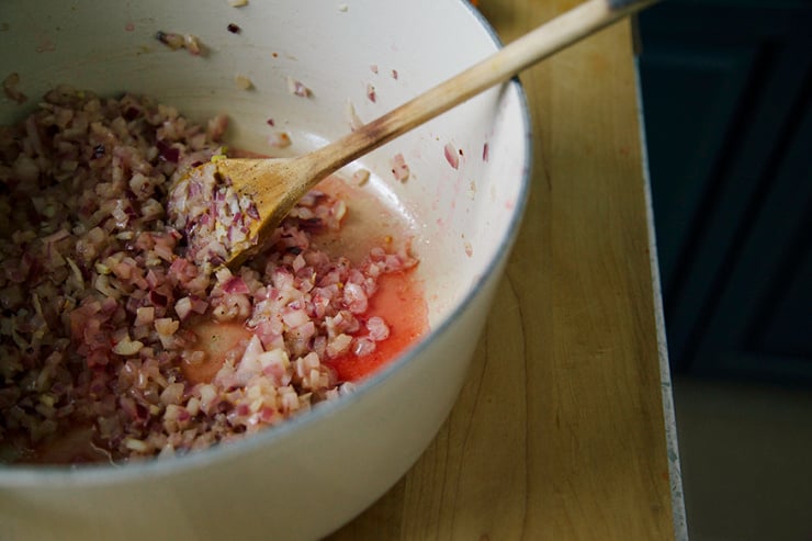 Image shows onions sauteeing in a pot.