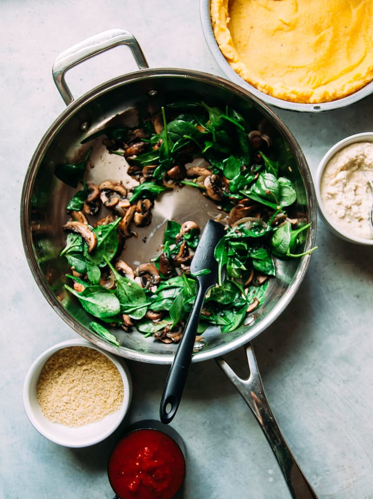 Image shows a saut&eacute; pan with cooked mushrooms and spinach.