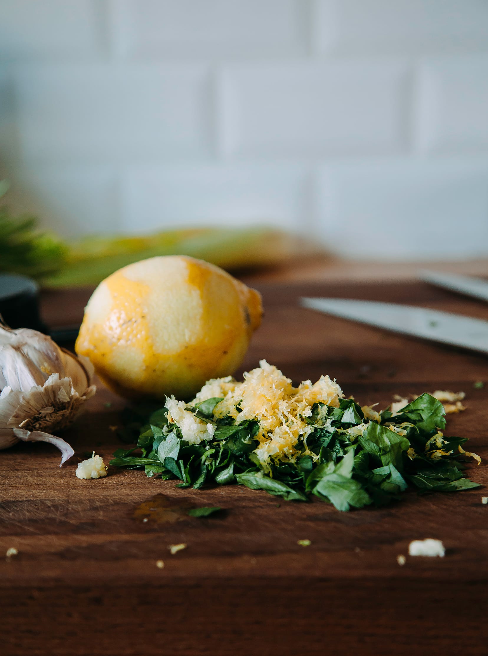 An up close shot of lemon zest mixed with chopped parsley on a cutting board.