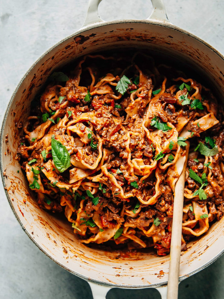 An overhead shot of a deep red, meaty vegan bolognese pasta in a pot.