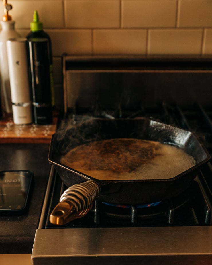 A 3/4 angle shot shows a skillet with a simmering liquid steaming away on a gas stove.