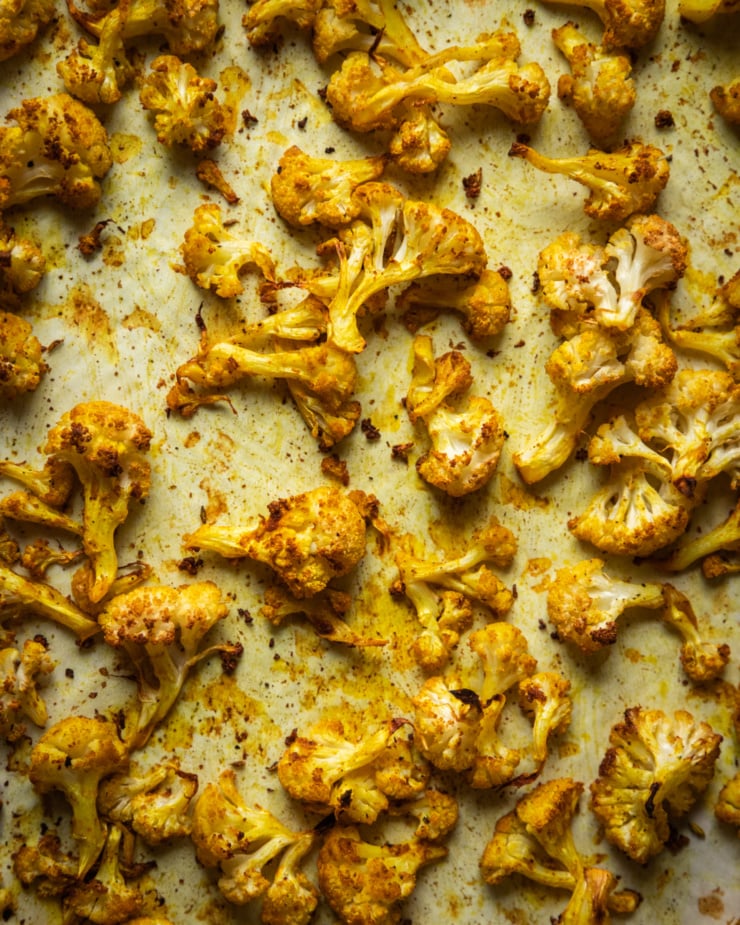 An overhead shot of spice-roasted cauliflower on a parchment lined baking sheet.