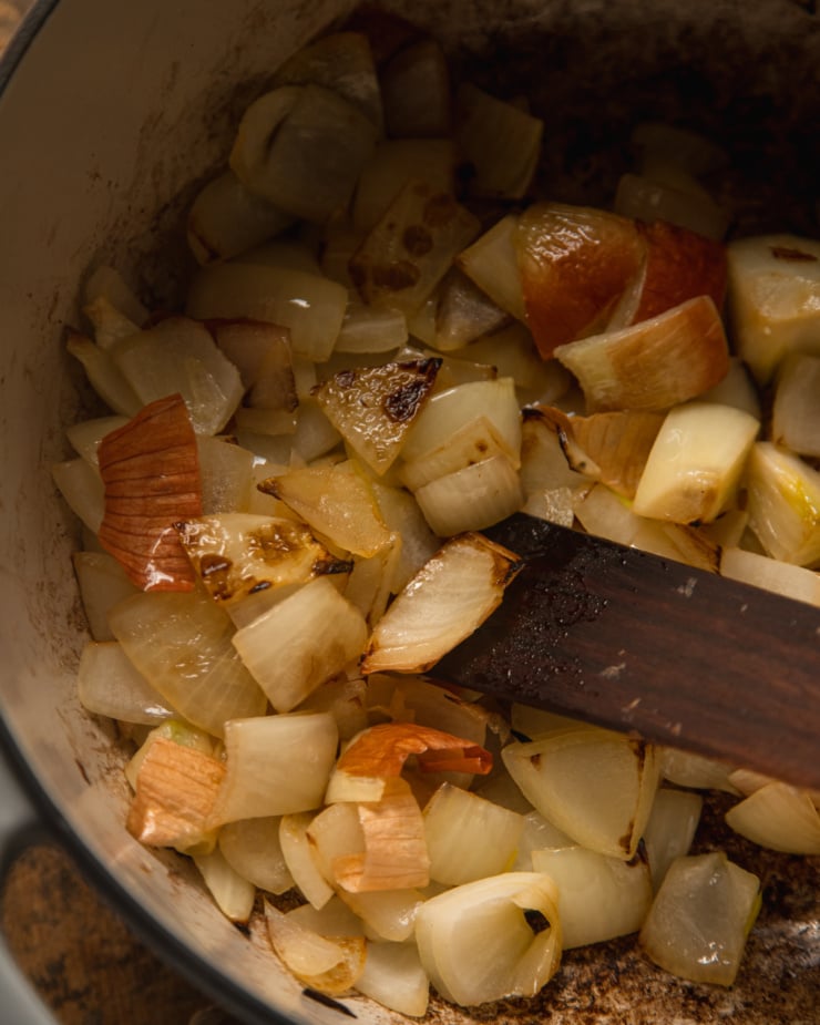 An overhead shot shows browned, chopped onions in a dutch oven-style pot.