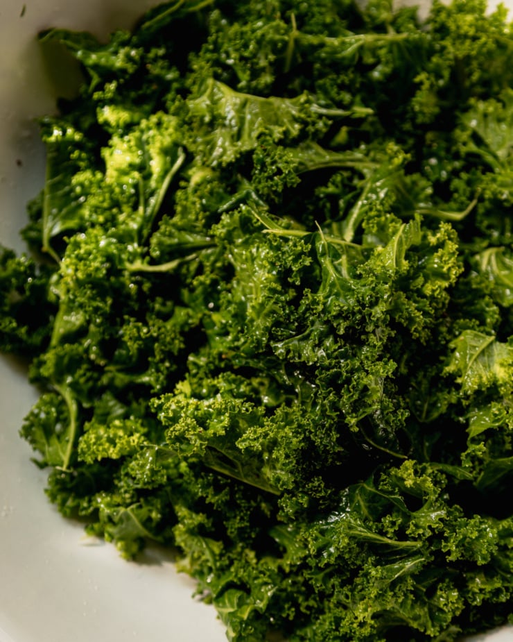 An up close shot shows chopped kale that has been massaged with olive oil, lemon juice, salt, and pepper.