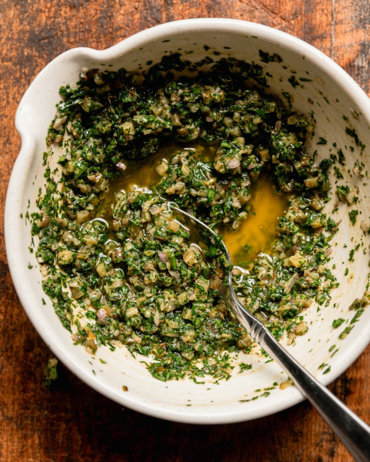 Overhead shot shows a bowl of dill pickles salsa verde, spoon sticking out.