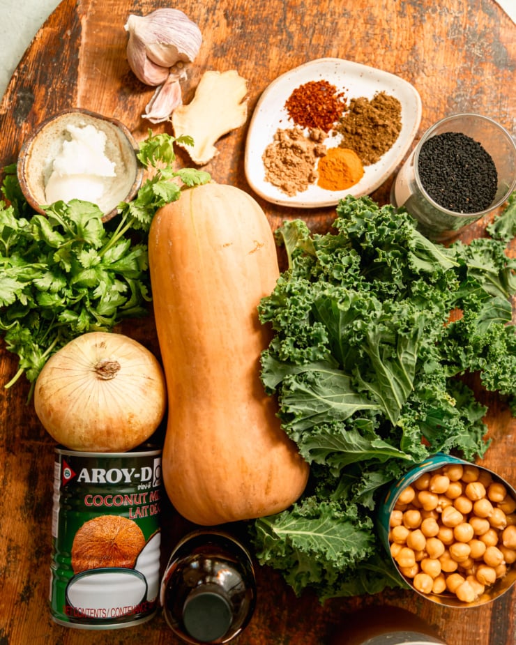 An overhead shot shows the ingredients needed for stews of chickpeas and kale. All ingredients are on rough wood boards.