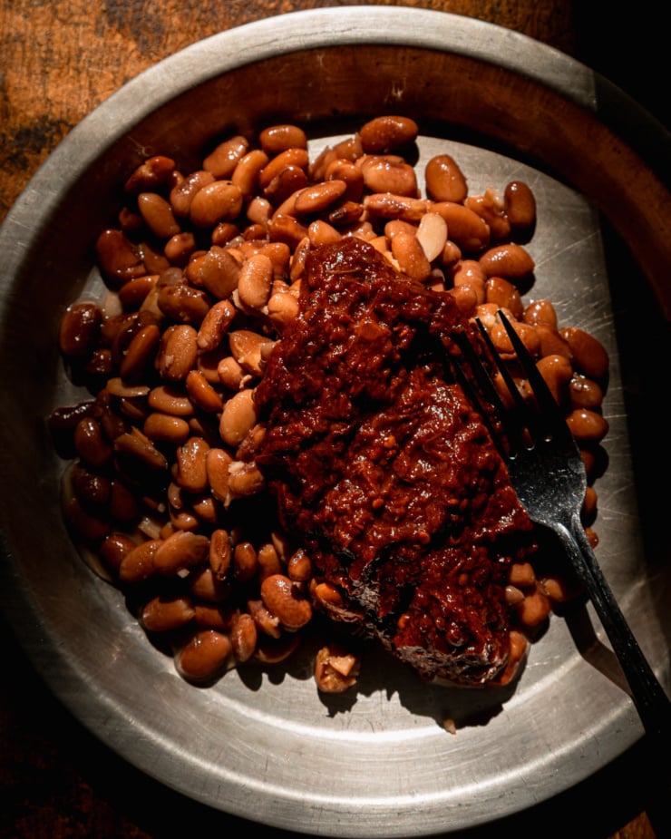 The overhead shot shows a light dish with pinto beans and thick chipotle salsa.