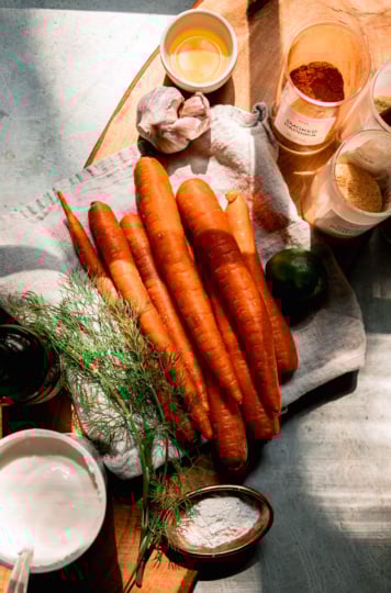 An overhead shot shows ingredients needed for oven-baked carrot fries and a creamy yogurt dip to go along with.