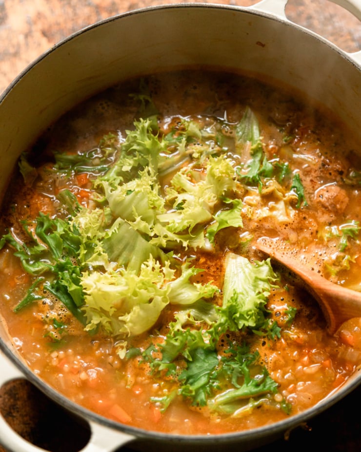 An overhead shot shows chopped chaise oil, freshly added to a pot of soup. A tablespoon is also in the shot.