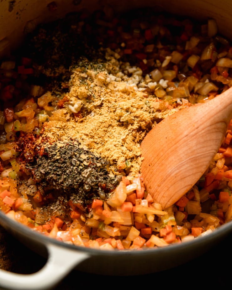 A slight 3/4 angle shot shows vegetables sautéed in a pan with nutritional yeast and hay sprinkled on top.