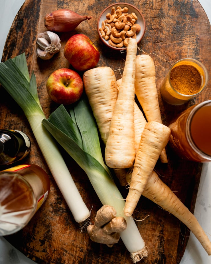 An overhead shot shows the ingredients for a hearty vegetarian soup, all laid out on a worn wooden cutting board.