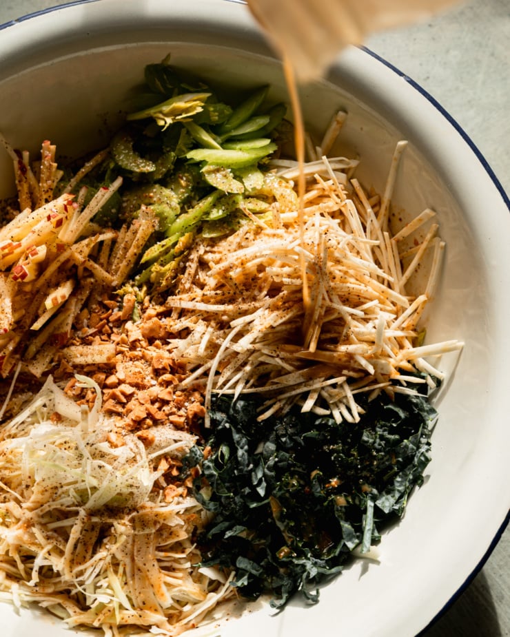 Top view shows maple peanut vinaigrette poured over shredded vegetables and apples.