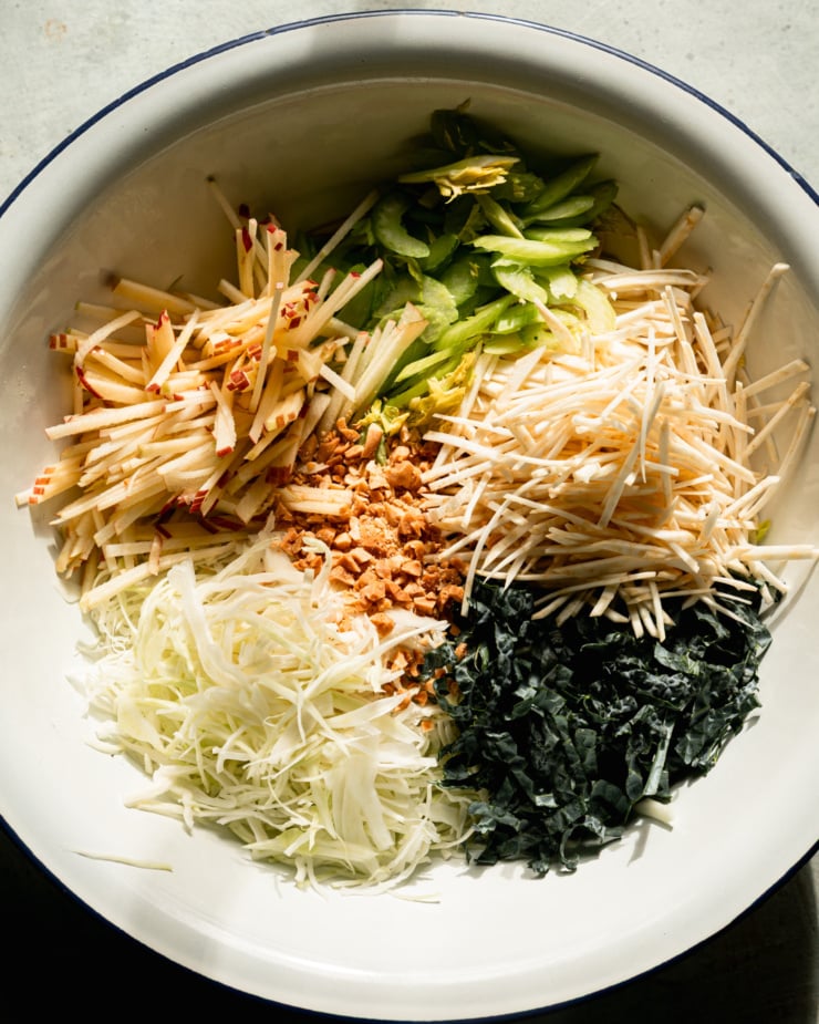 The overhead photo shows a large enameled bowl holding a pile of shredded vegetables and fruits.