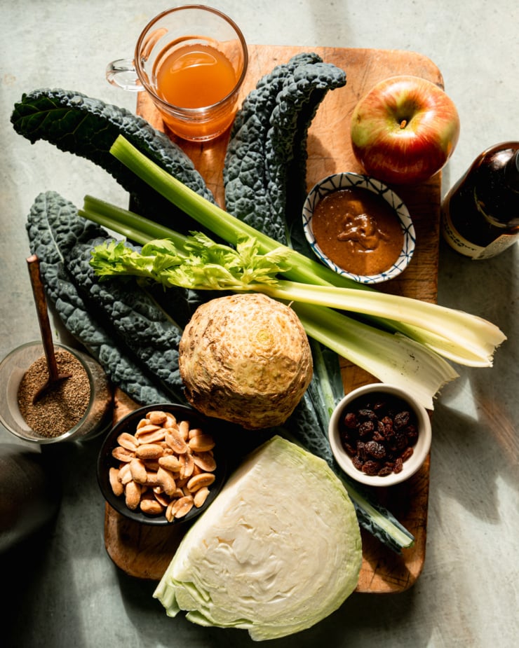 An overhead view shows the ingredients for a celery root salad, including kale, cabbage, celery and apples.