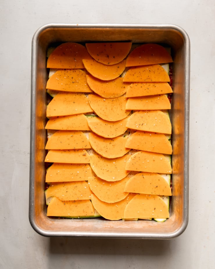 Top-down photo shows thinly sliced ​​butternut squash in a baking dish.