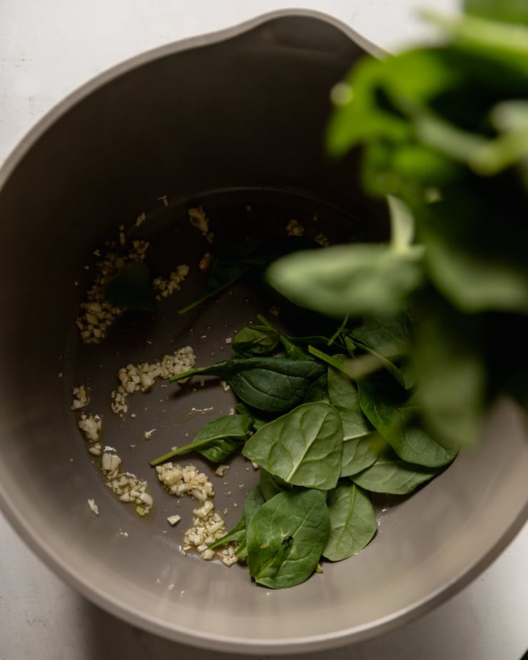 The top view shows that the fried minced garlic and baby spinach are poured into the pot.