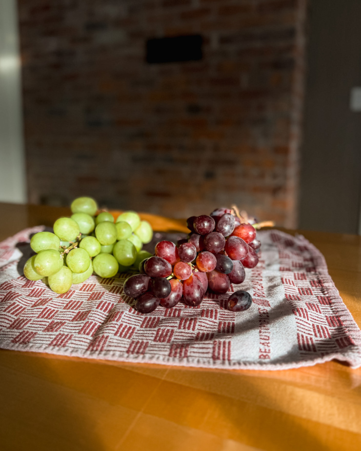 A head on shot shows two bunches of grapes drying on a tea towel on the counter.