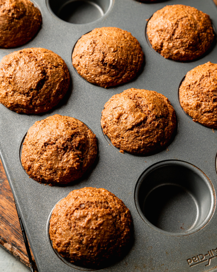 An overhead shot shows freshly baked vegan bran muffins, still in the muffin tin.