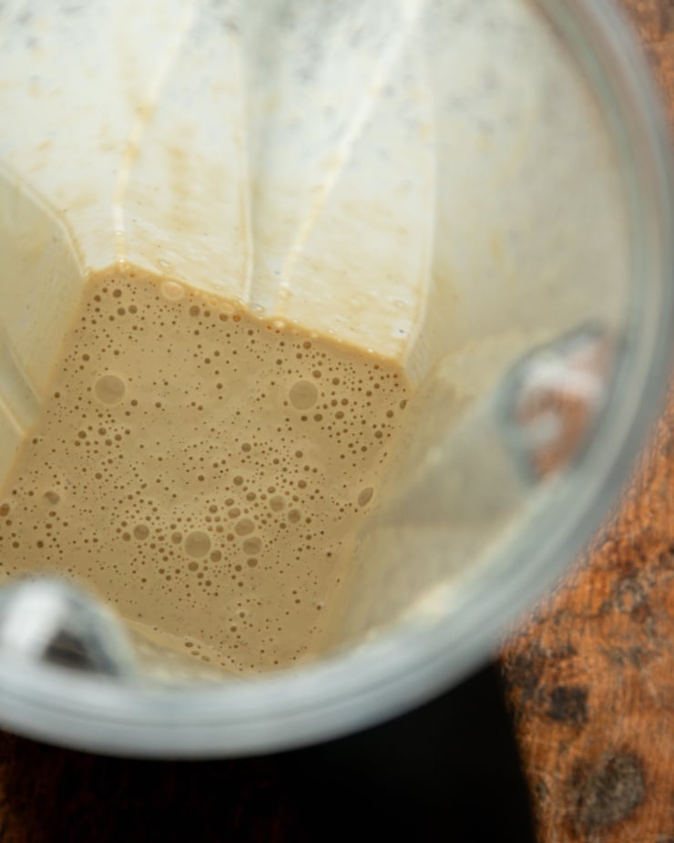 An overhead shot shows blended up creamy garlic cashew dressing in a blender pitcher.