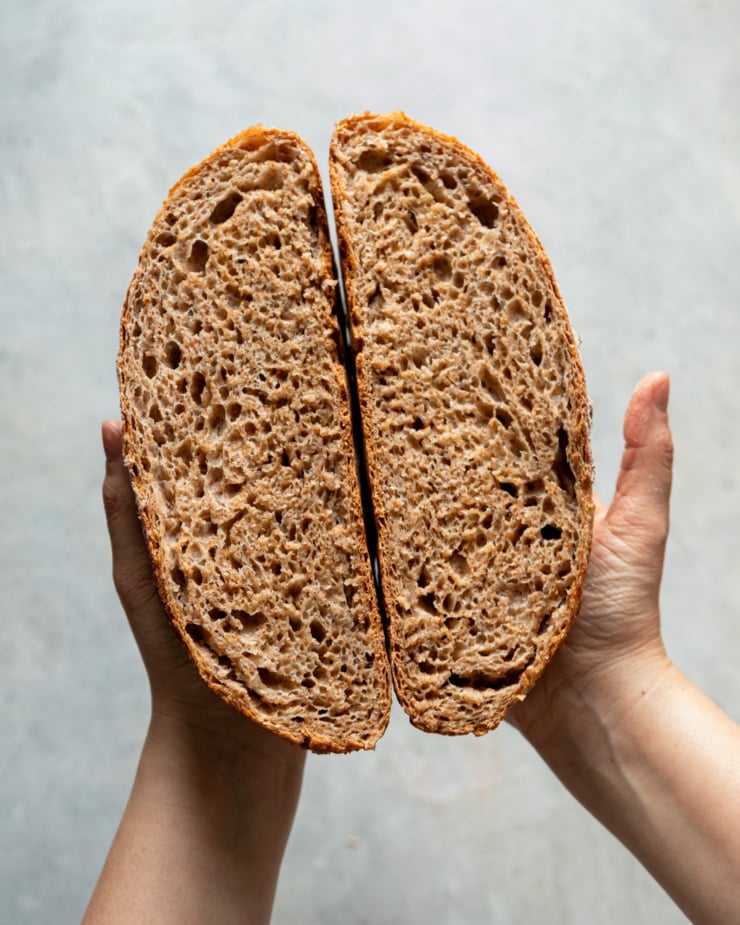 An overhead shot shows a loaf of no-knead whole wheat bread split in half, revealing a puffy open crumb.