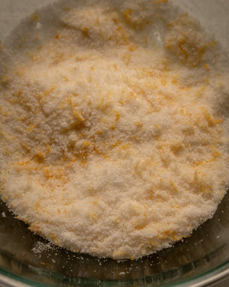 An up close, overhead shot shows cane sugar and lemon zest in a glass bowl.