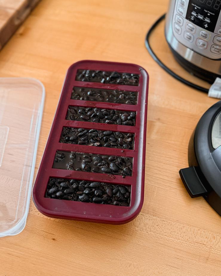 An overhead shot shows a batch of cooked black beans in a silicone freezer tray with 6 half cup portions.