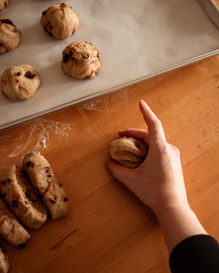 An overhead shot shows a hand shaping portions of dough into balls.