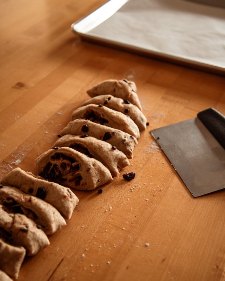 A 3/4 angle shot shows a batch of vegan hot cross bun dough that has been portioned on a counter. A baking sheet is nearby.