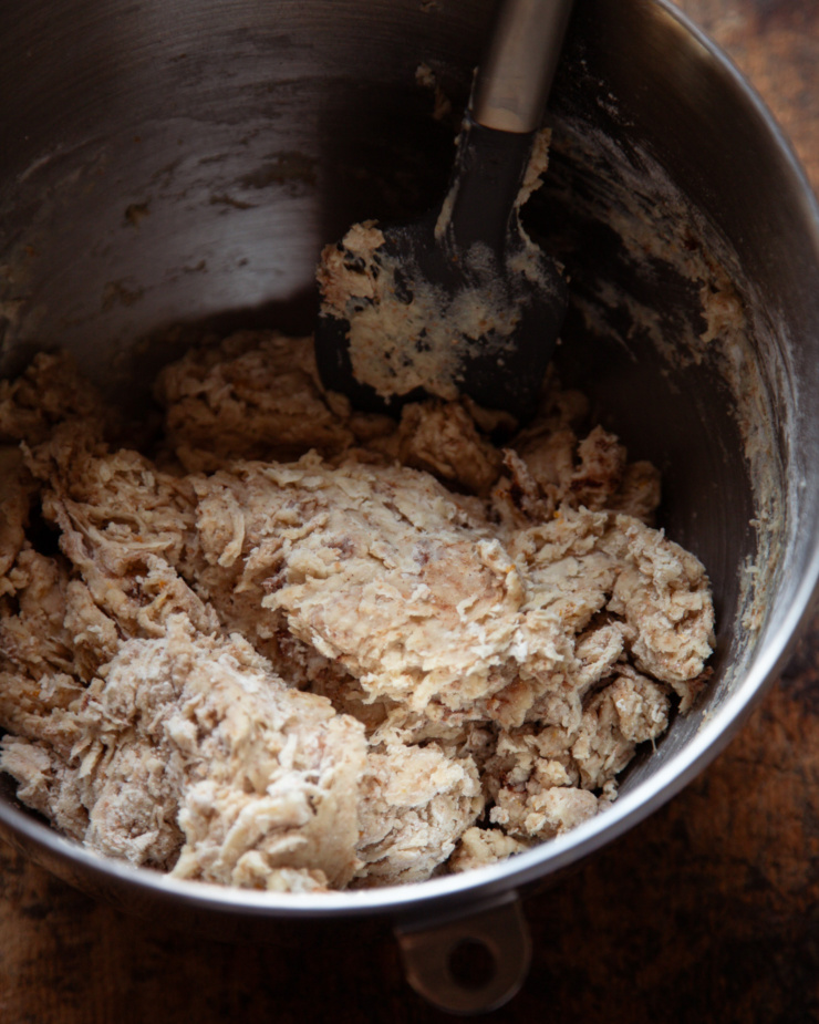 An overhead shot shows a shaggy, just-mixed dough mixture in a bowl with a spatula.