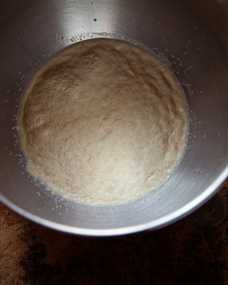 An overhead shot shows a foamy yeast and soy milk mixture in a mixing bowl.