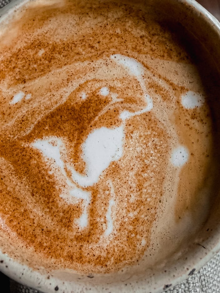 An up close, overhead shot shows a frothy nut milk latte.