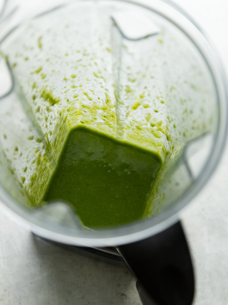 Overhead view of basil lime dressing blended smooth in a blender jar.