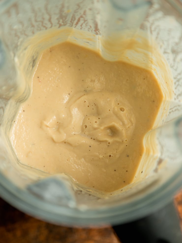 Close-up of a smooth, creamy tan-colored caramelized onion, cashew and yellow squash pasta sauce in a blender.