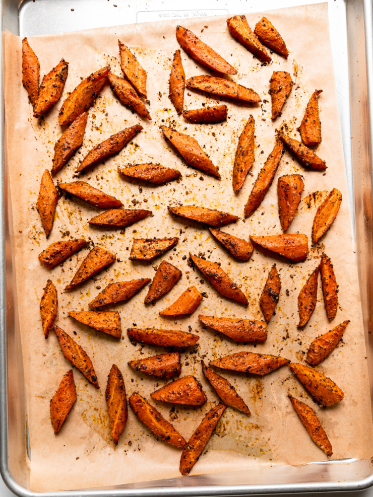 Carrots cut on the diagonal and roasted with za'atar and black lime on a parchment-lined baking sheet.
