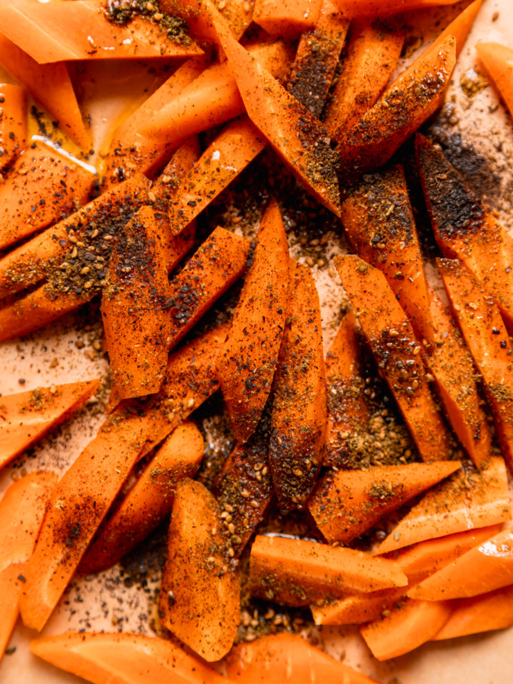 Close-up of raw carrot pieces tossed in olive oil, za'atar and ground black lime before roasting.